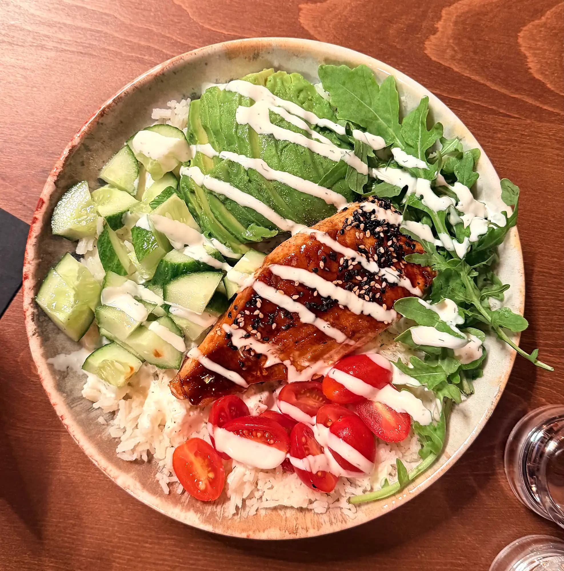 Bowl mit gegrilltem Hähnchen, Avocado, Reis, Gurke, Tomaten und Rucola