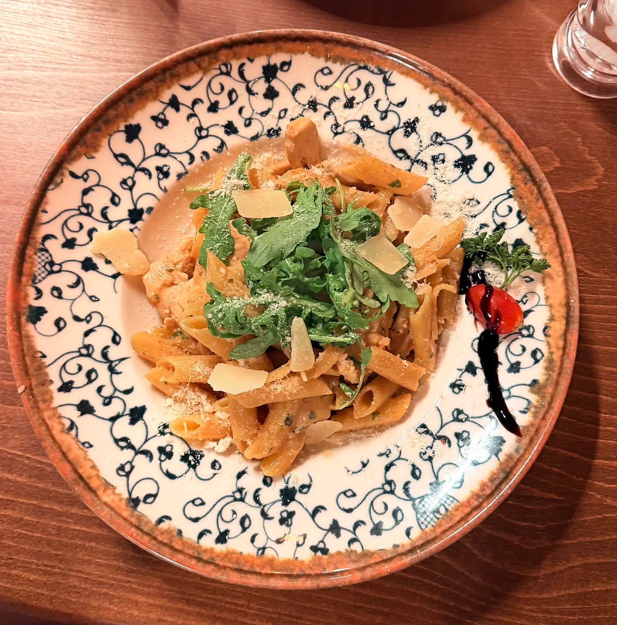 Penne with rocket and parmesan on a patterned plate