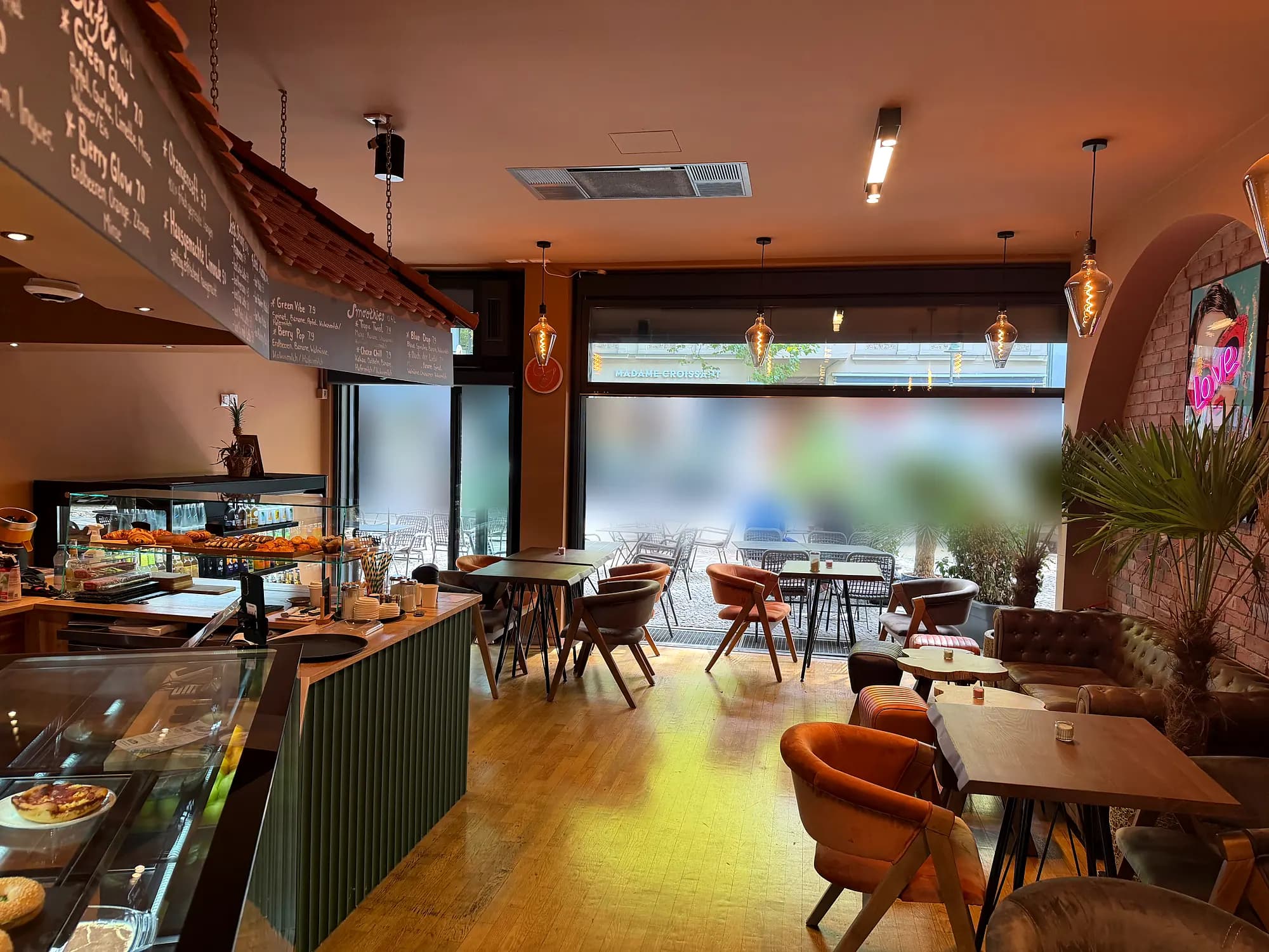 Dining room with a large window front to the street, counter and display on the left, upholstered chairs on the right