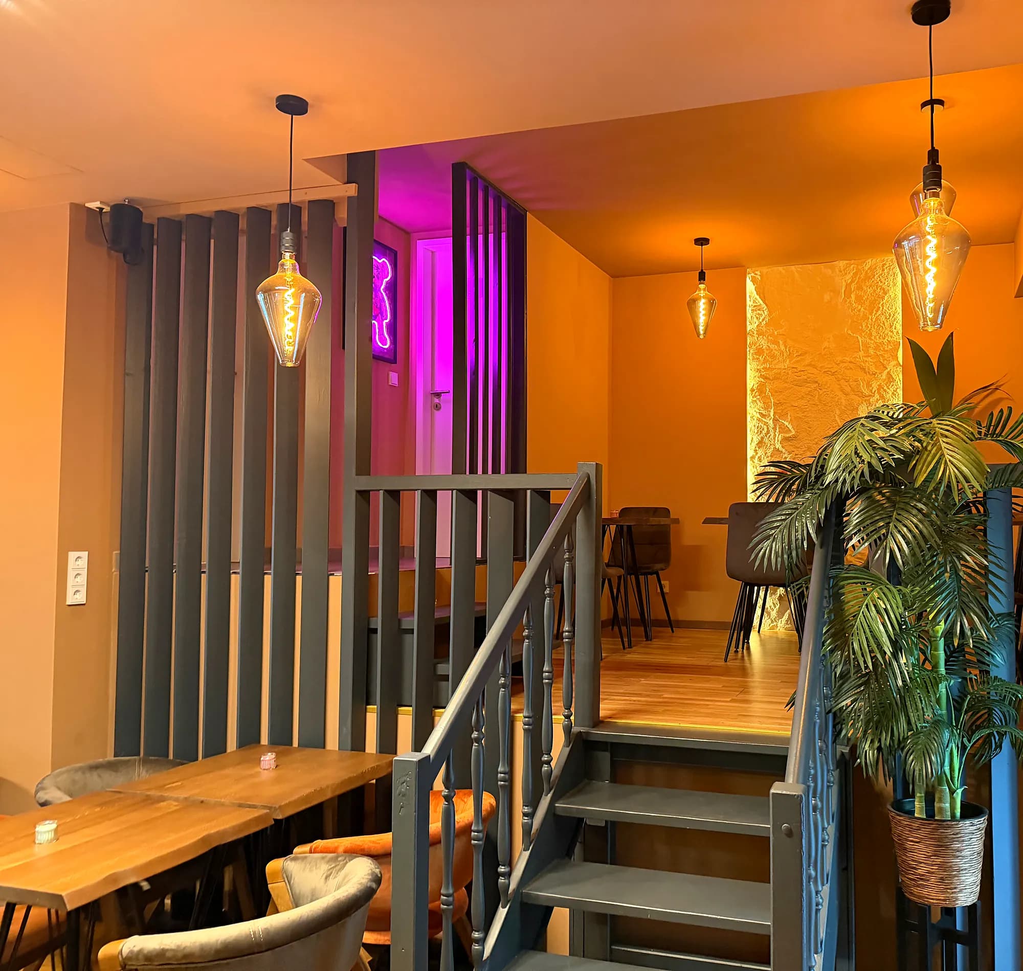 Way up to the gallery with grey metal stairs, a palm and pendant lamps