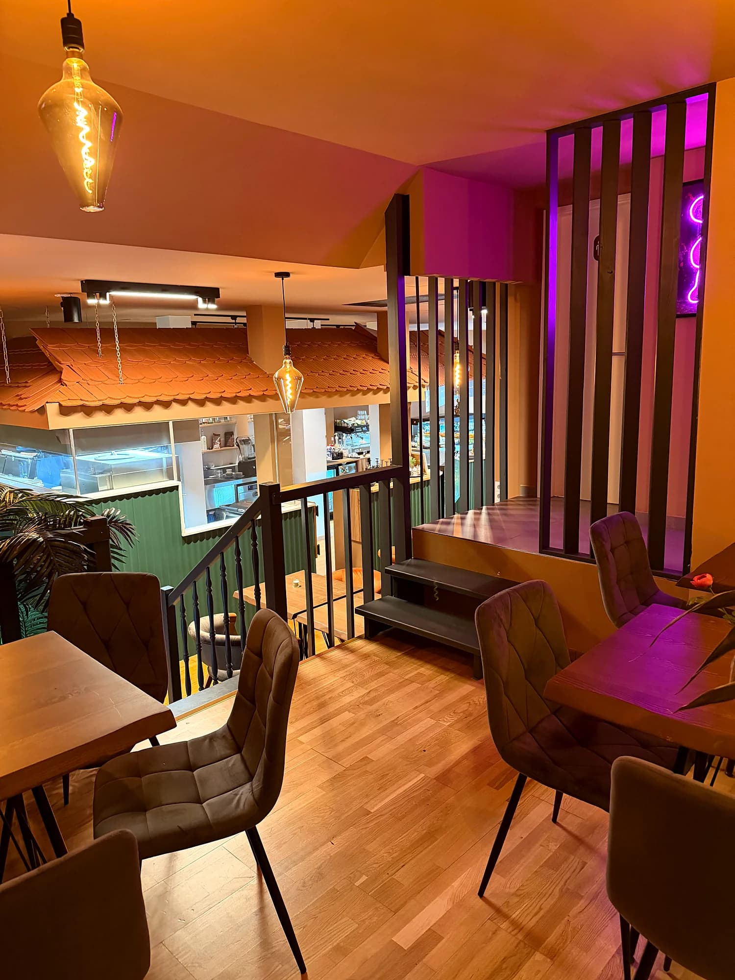 View from the gallery over the stair railing and tables to the green kitchen counter