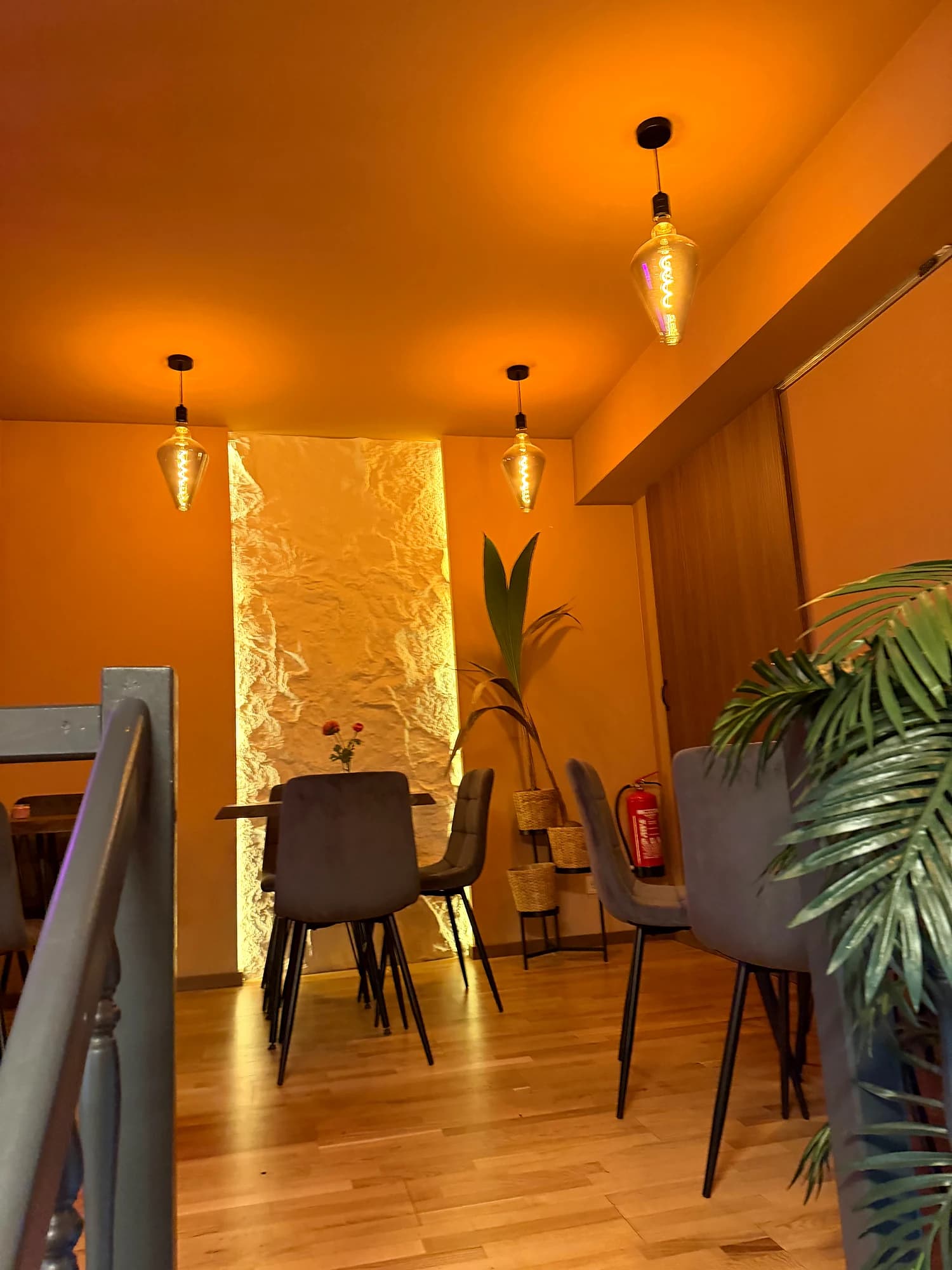 Gallery with a golden-lit wall, tables, chairs and plants